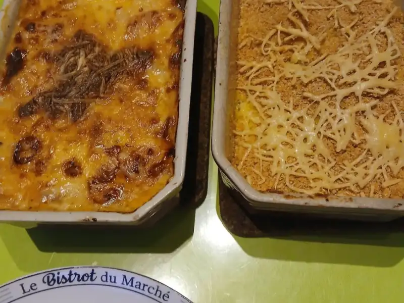 Goudbruin gegratineerde prei en huisgemaakte puree met paneermeel, in twee ovenschalen op een groene tafel
