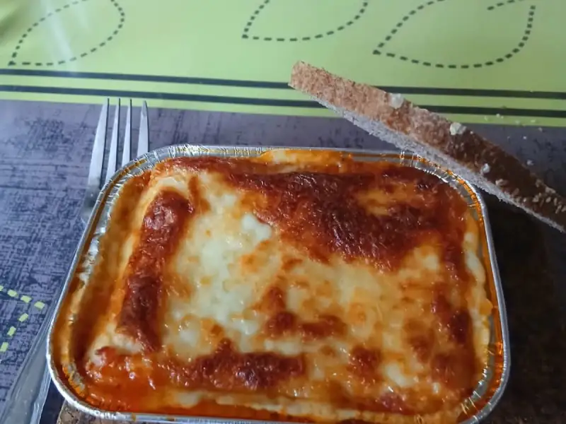 Huisgemaakte individuele lasagne: een mooi gegratineerd aluminium bakje met een sneetje geroosterd brood